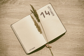 october 14. 14th day of month, calendar date.Blank pages of notebook are beige, with dried...