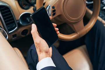 Smartphone in hand in front of steering wheel