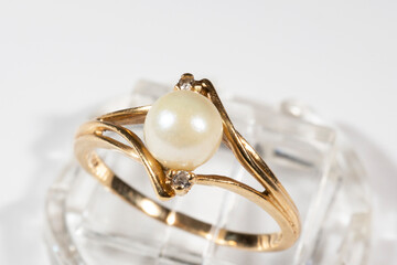 A gold ring with a white round pearl and two small diamonds