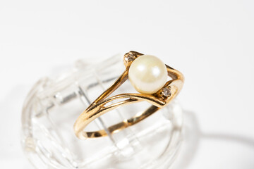 A gold ring with a white round pearl and two small diamonds