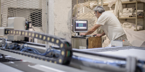 Technician works on CNC digital cutter machine for cutting textile