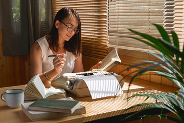 Attractive female writer in glasses looking for inspiration to start a new novel on her retro...
