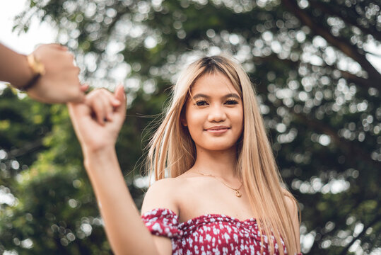 A Young Woman Does A Pinky Swear With Her Friend While Smiling At The Camera. A Promise Between Two Friends.