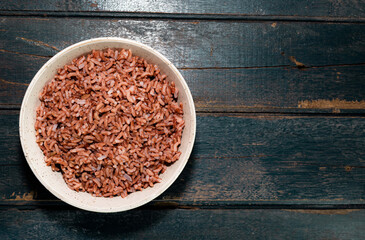 Obraz na płótnie Canvas Rice red in bowl isolated on blue background. Asian food and drink concept.