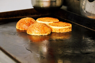 Hamburger breads or burger buns are roasting on the grill