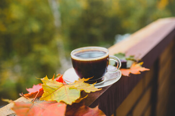 a cup of coffee on the balcony and maple leaves
