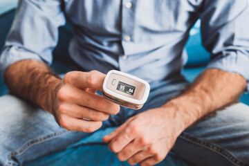 Measurement of oxygen level and pulse rate with a portable pulse oximeter - a man monitors his...