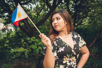 A pretty big-boned woman looks ardently at the Philippine Flag. A proud citizen celebrating.