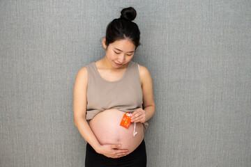 A young pregnant Asian woman holding a lucky charm