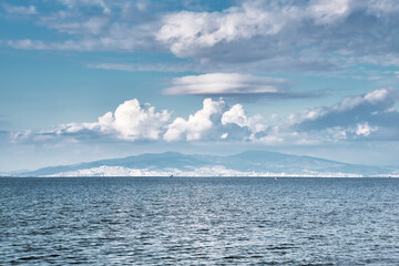 Minimalistic seascape with sea, sky, sand and an island at the horizon.