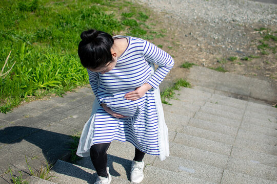 A young pregant Asian woman hard to climb the stairs