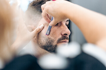 Selective focus on the face of a costumer being shaved by hand with a razor