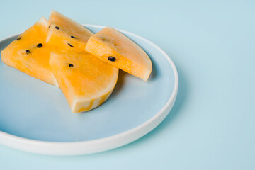 Slices of yellow watermelon on a plate on a blue background