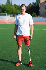 Obraz premium Portrait of young caucasian male athlete brunette with prosthetic leg on the stadium on the field