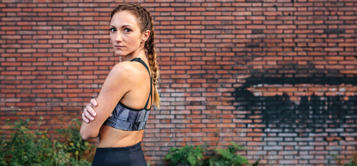 Sportswoman with boxer braids posing in front of a brick wall
