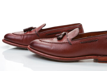 Pair of Traditional Formal Stylish Brown Pebble Grain Tassel Loafer Shoes Together In Line Against White Reflective Surface