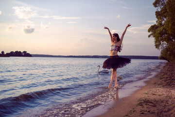 Vulnerable And Sensual Japanese Ballet Dancer in Black Tutu Posing Near Seashore During Ballet Pas in Summertime in Dance Pose With Lifted Hands Outdoor.