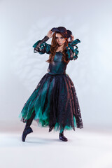 Classical Ballet Concepts. Artistic Japanese Female Ballet Dancer In Flying Bat Stage Costume Posing in Dance Pose With Lifted Hand and Pattern Against White Background