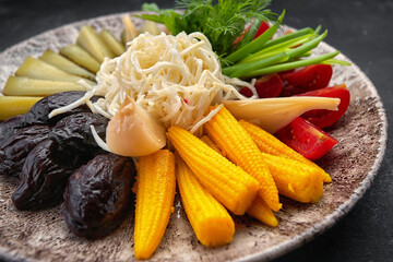 Pickled vegetables on a dark background cucumbers tomatoes herbs