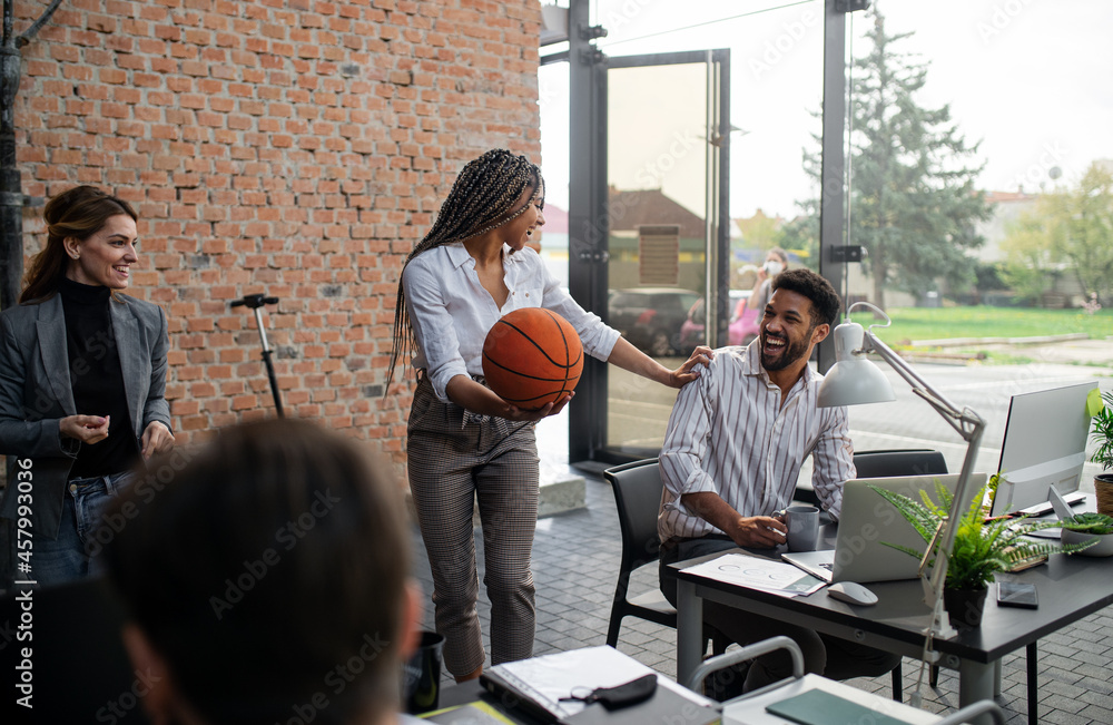 Wall mural Cheerful young businesswoman having fun with ball in office, take a break concept.