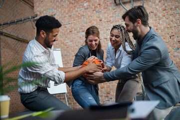 Group of cheerful young businesspeople playing basketball in office, taking a break concept.