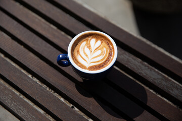 cup of cappuccino with latte art with spoon on the wooden background