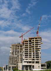 Fototapeta na wymiar construction site with a concrete high-rise skyscraper building and scaffolding and two cranes on top