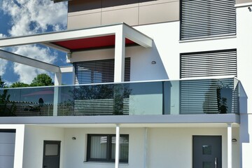Integrierte Pergola mit Edelstahl-Attika als Sonnenschutz und Metallbalkon mit Rauchglas-Sichtschutz am mittleren Geschoss eines neu gebauten Einfamilienhauses