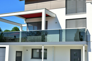 Balkon und Pergola als Sonnenschutz an moderner Hausfront mit Edelstahl-Glas-Geländer als...