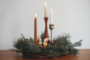 Stylish christmas wreath with candles and pine trees decorations on wooden table on background of...