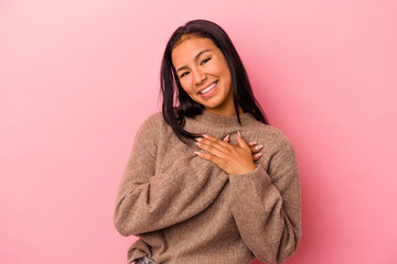 Young latin woman isolated on pink background  has friendly expression, pressing palm to chest. Love concept.