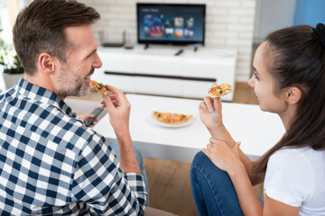 Couple watching TV while eating pizza