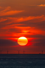 Offshore wind farm in the Baltic Sea in the light of the setting sun with ships