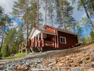 Guest house made of logs at a tourist base in the middle of the pine forest in a sunny day.