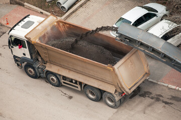 Cold milling machine loading powdered asphalt into dump truck on the street. Road construction work. Maintenance on the street. 
