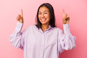 Young latin woman isolated on pink background  indicates with both fore fingers up showing a blank...