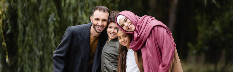 Arabian family with children smiling at camera in park, banner