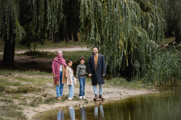 Arabian family smiling at camera near lake in park