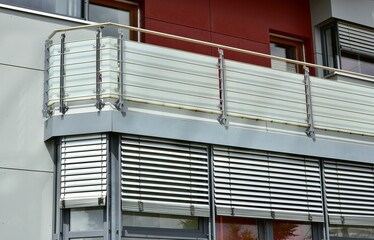 Moderner Balkon mit Sichtschutz aus Mattglasplatten und Metall-Geländer an einer Neubau-Hausfront