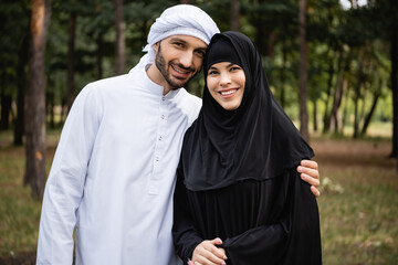 Muslim couple in traditional clothes smiling at camera outdoors
