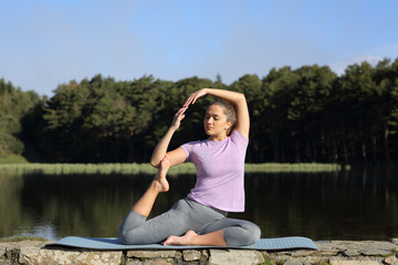 Fototapeta na wymiar Woman doing yoga in a lake on summer
