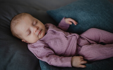 Portrait of newborn baby girl, sleeping an lying on sofa indoors at home.