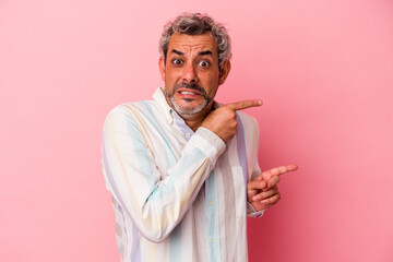 Middle age caucasian man isolated on pink background  shocked pointing with index fingers to a copy space.
