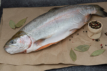 A whole salmon on paper on a black marble background