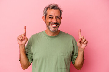 Middle age caucasian man isolated on pink background  indicates with both fore fingers up showing a...