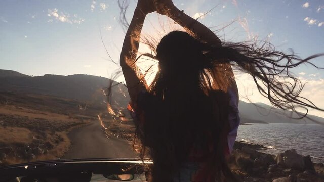 Sporty sexy woman standing in cabriolet. Best friends spend summer time together. The girls are happy and enjoy life. The road by car to the sea. Friendship and love forever. The beauty of Greece.