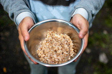 Hungry man holding a metal bowl of porridge