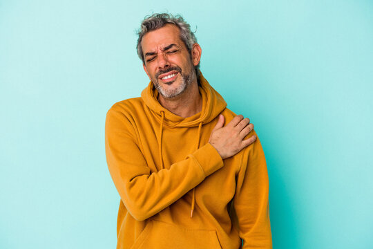 Middle age caucasian man isolated on blue background  having a shoulder pain. - Powered by Adobe