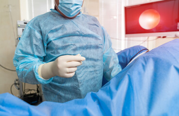 Surgeon in blue uniform working with equipment. Professional medical specialist working with instruments.
