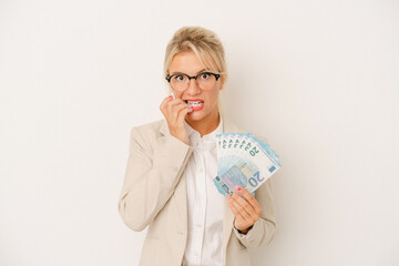 Young business Russian woman holding banknotes isolated on white background biting fingernails, nervous and very anxious.